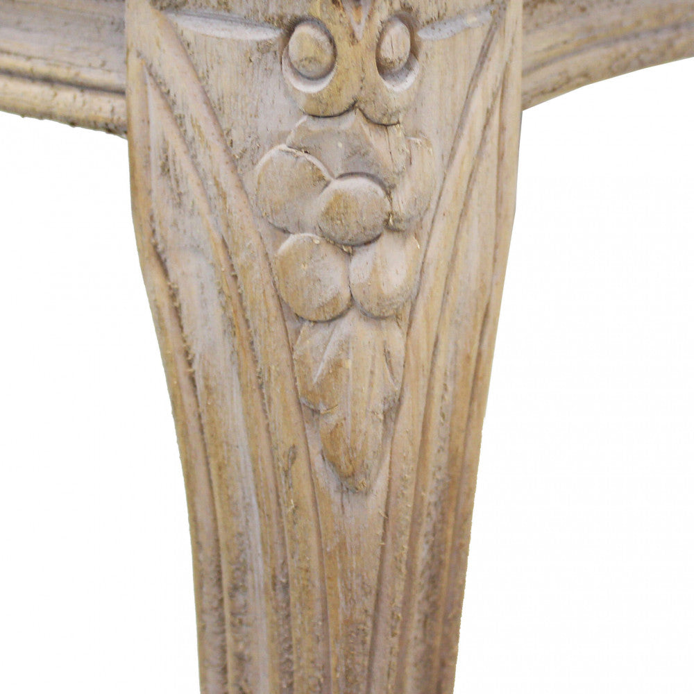 Dettaglio ravvicinato della gamba in legno massello con intagli floreali artigianali.