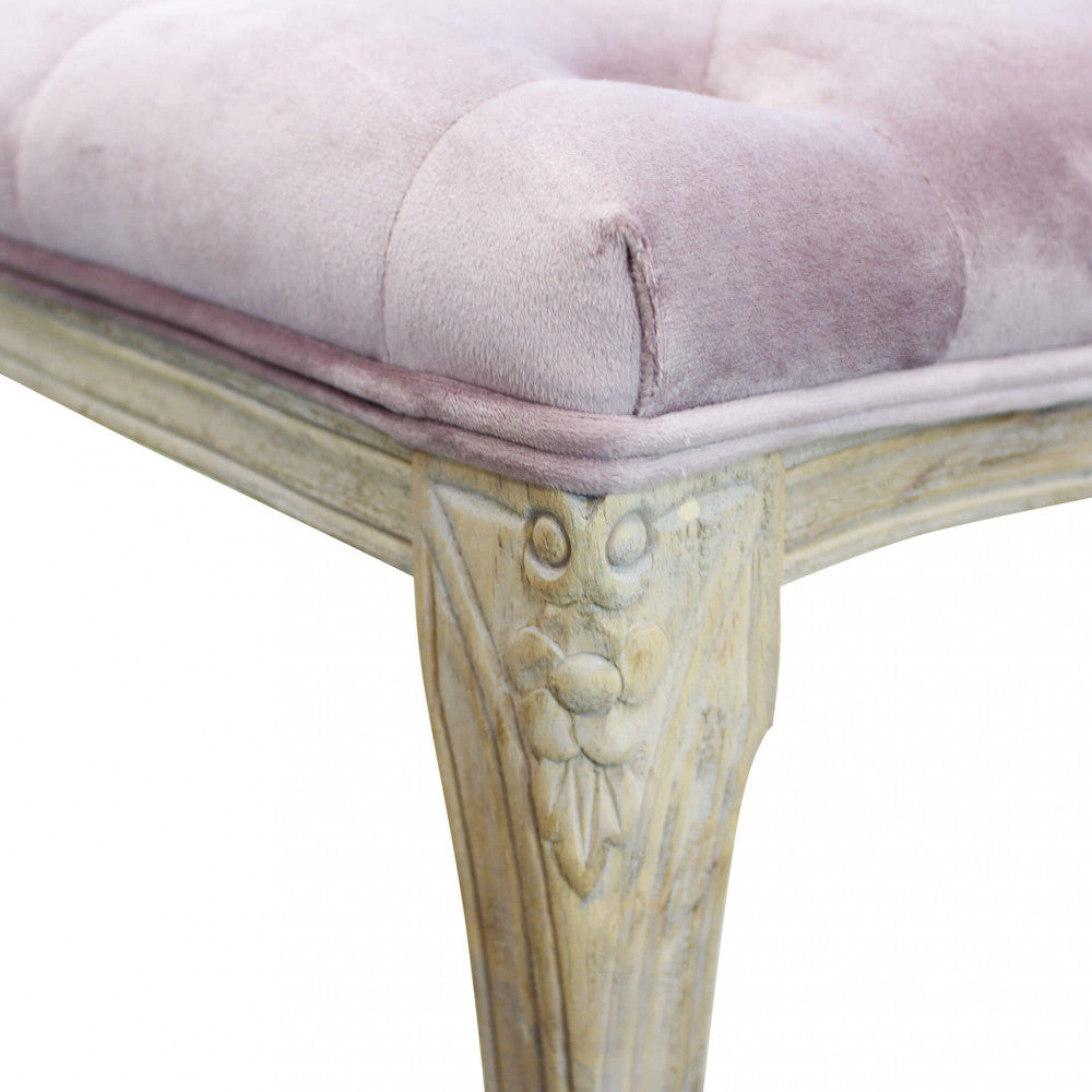 Primo piano dell'angolo della panca che mostra il velluto capitonné e l'intaglio floreale sulla gamba in legno.