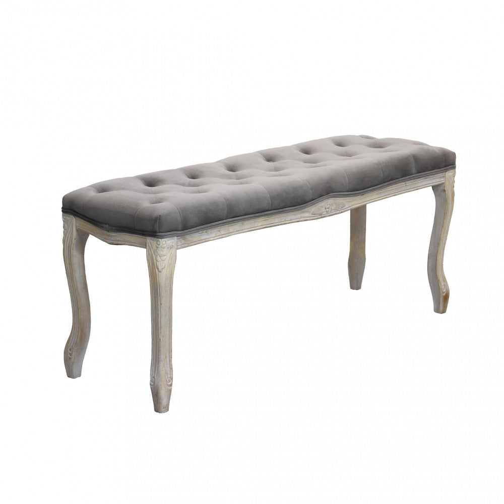 Vista angolare della panca Misty che mostra la seduta capitonnè in velluto taupe e le gambe in legno sinuose.