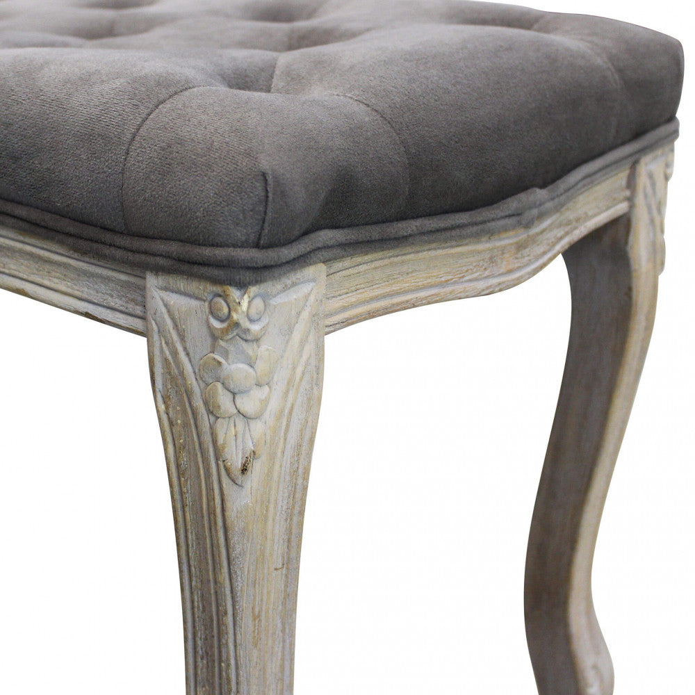 Dettaglio ravvicinato dell'angolo della panca, con intaglio floreale sul legno decapé e bordo in velluto.