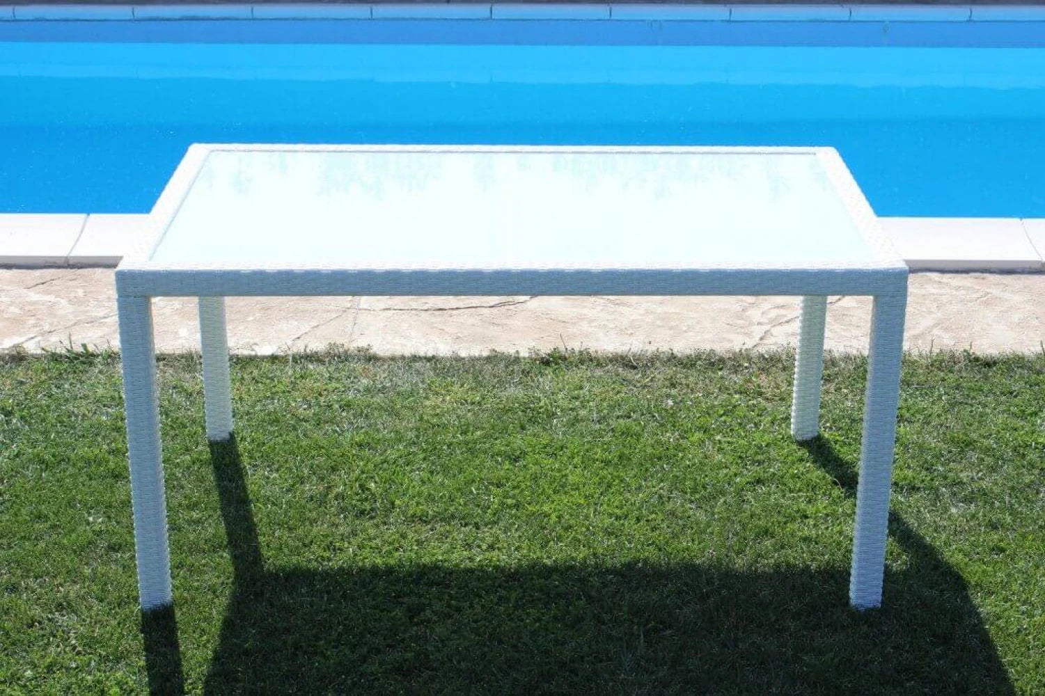 Tavolo da pranzo Azore 150x90 Bianco, struttura in alluminio rivestita in polyrattan e piano in vetro temperato, ambientato in giardino