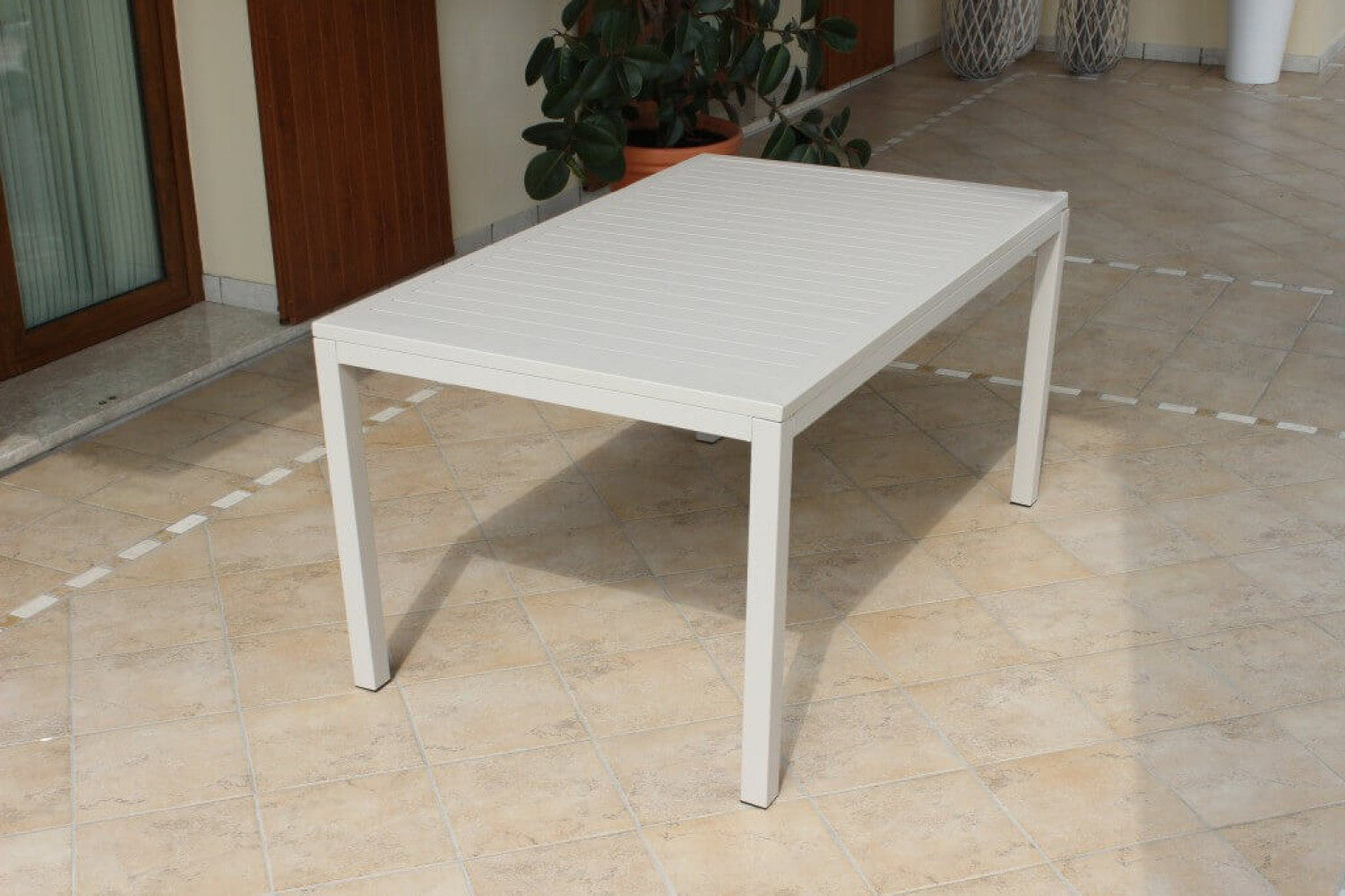 Panoramica Tavolo Milo 150x90 cm in alluminio tortora, ambientato su una terrazza con sedie abbinate, che ne evidenzia il design pulito e la stabilità | Albert Stock