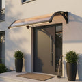 Pensilina in policarbonato grigio scuro installata sopra una porta d'ingresso moderna, illuminata dalla luce LED integrata al tramonto.