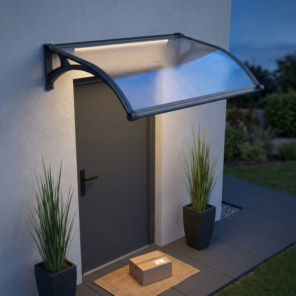 Dettaglio serale della pensilina da esterno con sistema LED acceso, che proietta una luce calda sulla facciata e sulla porta d'ingresso.