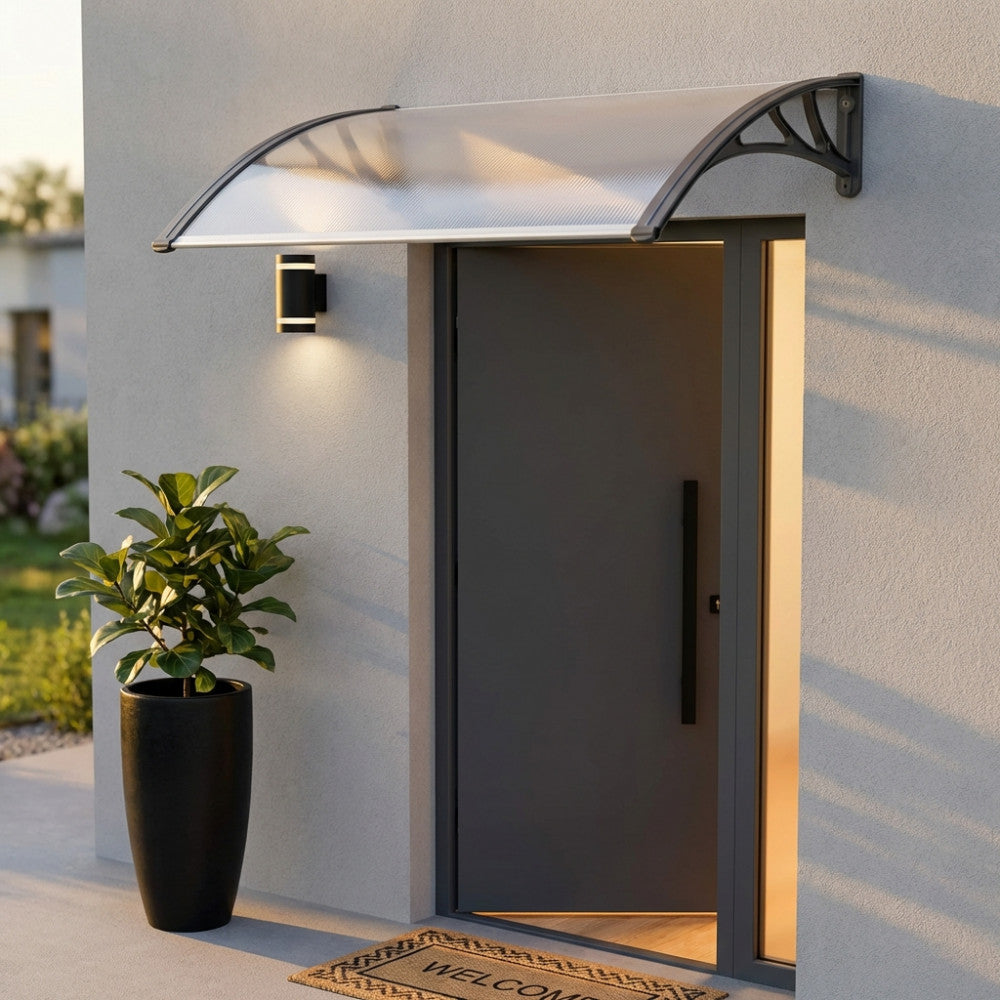 Dettaglio della pensilina alveolare opaca montata su una facciata moderna con porta d'ingresso grigia e illuminazione a parete.