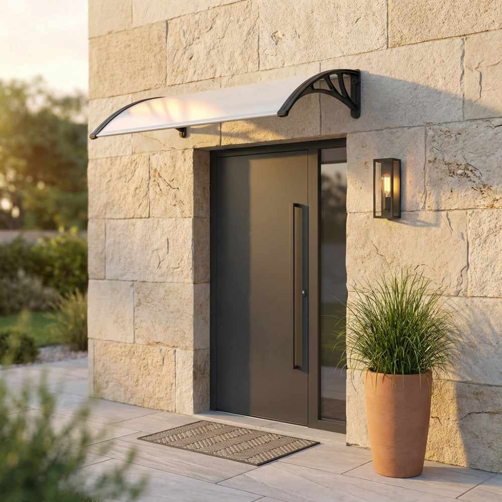 Copertura per esterni RAIN montata su una parete in pietra testurizzata sopra una porta moderna grigia, affiancata da una lampada di design.