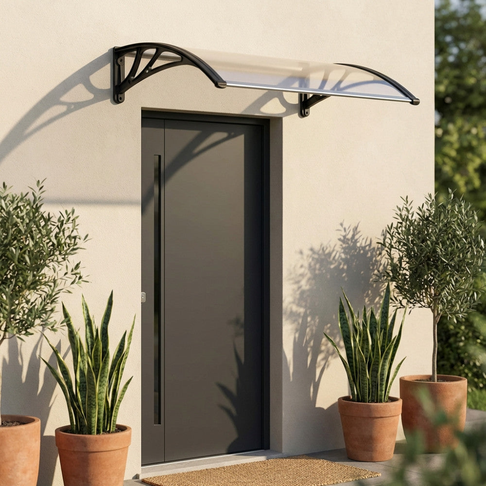 Vista frontale della pensilina Rain trasparente grigio, che protegge un ingresso elegante affiancato da piante in vasi di terracotta.