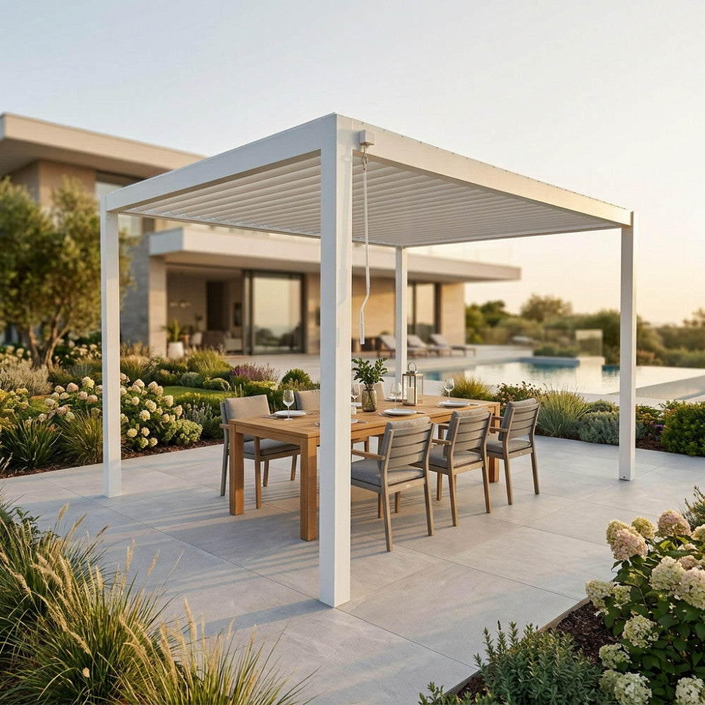 Pergola bioclimatica in alluminio bianco allestita con tavolo da pranzo in teak e sedie in un giardino lussuoso.