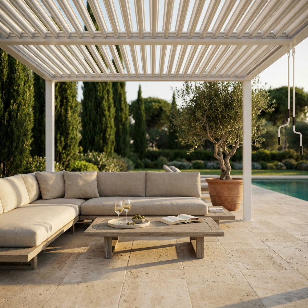 Gazebo pergola bioclimatica bianca posizionata a bordo piscina con un divano componibile beige e tavolino in legno.