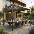Gazebo pergola bioclimatica 3x4 grigio scuro allestita con tavolo da pranzo in legno e sedie scure su un patio in pietra.