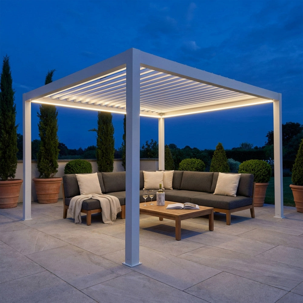 Pergola bioclimatica 4x4 bianca illuminata a LED di sera con salotto outdoor.