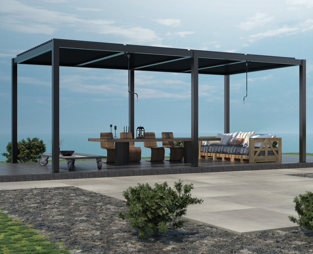 Pergola bioclimatica installata su una terrazza vista mare, arredata con tavolo da pranzo e divano in legno.