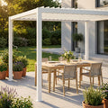 Pergola bioclimatica manuale in alluminio bianco, allestita con un elegante tavolo da pranzo in legno di teak e sedie in corda intrecciata su un patio soleggiato.