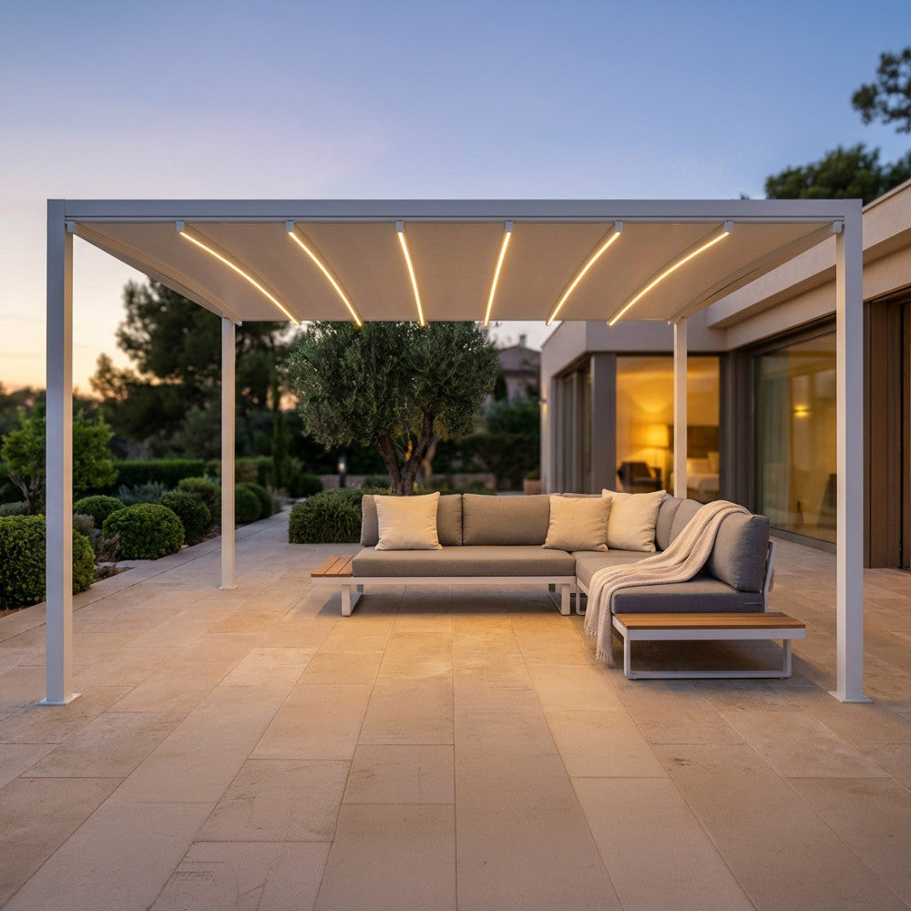 Gazebo pergola retrattile motorizzata 3x3 in alluminio bianco con illuminazione LED accesa al tramonto, allestita con salotto da esterno.