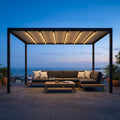 Pergola retrattile motorizzata in alluminio antracite illuminata da luci LED integrate, allestita su una terrazza panoramica al tramonto.