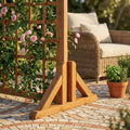 Piedino doppio in legno marrone che sostiene una griglia con rose rampicanti su un patio in pietra.