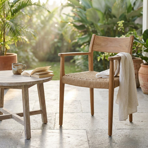 Dettaglio della poltrona Agra in teak illuminata dalla luce naturale in un giardino lussureggiante.