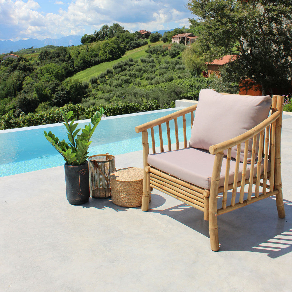 Poltrona BRONX allestita a bordo piscina con piante decorative e lanterne.