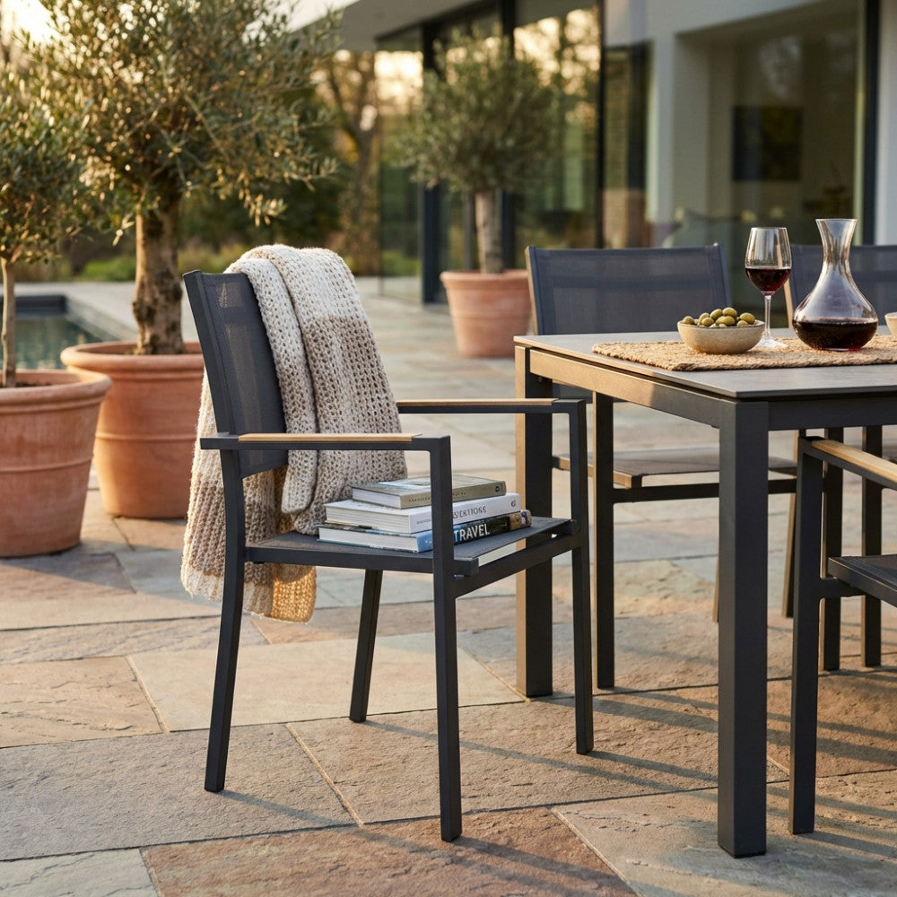 Dettaglio della poltrona Brooklyn con braccioli marrone chiaro e plaid decorativo in un patio moderno.