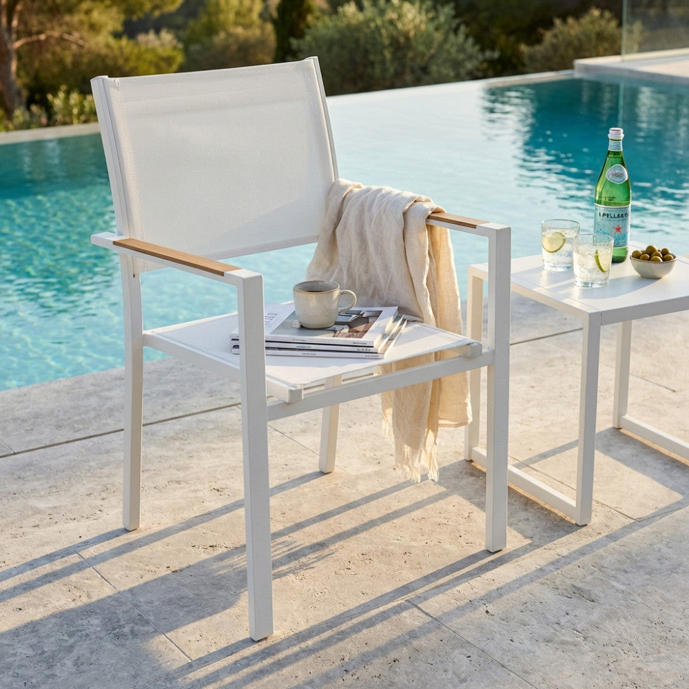 Poltrona Brooklyn in textilene bianco con un telo e una tazza appoggiati, a bordo piscina.