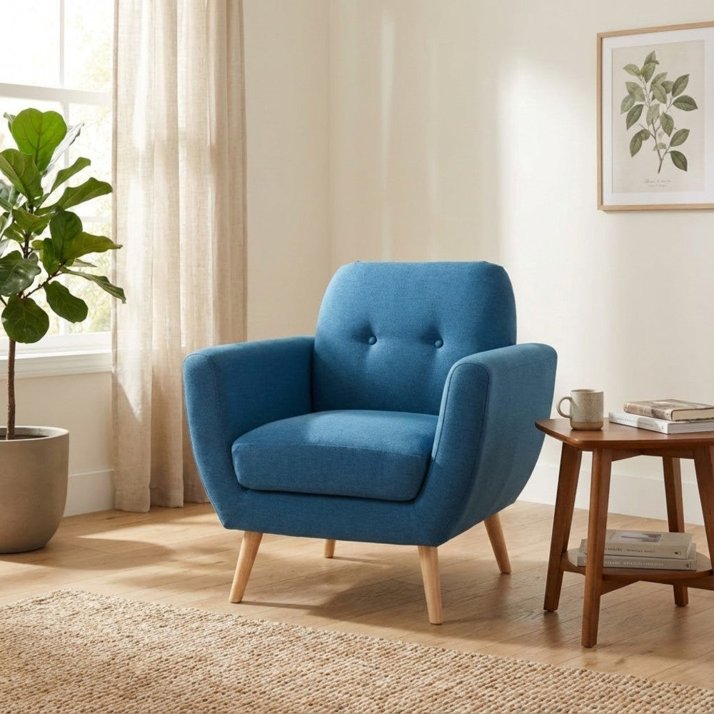 Poltrona moderna Burton blu posizionata in un angolo relax con tavolino in legno scuro, libri e una grande pianta in vaso.