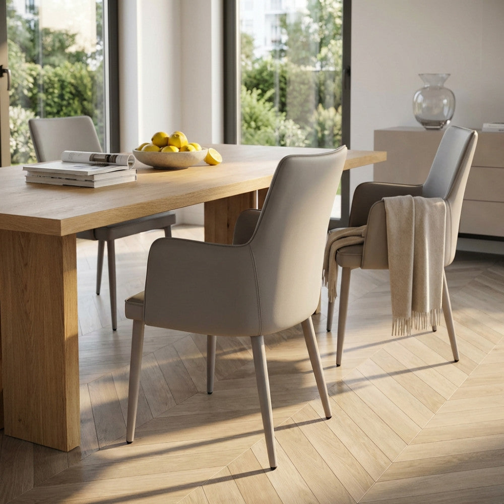 Coppia di poltrone grigio chiaro attorno a un tavolo da pranzo in rovere, con un morbido plaid appoggiato sullo schienale.