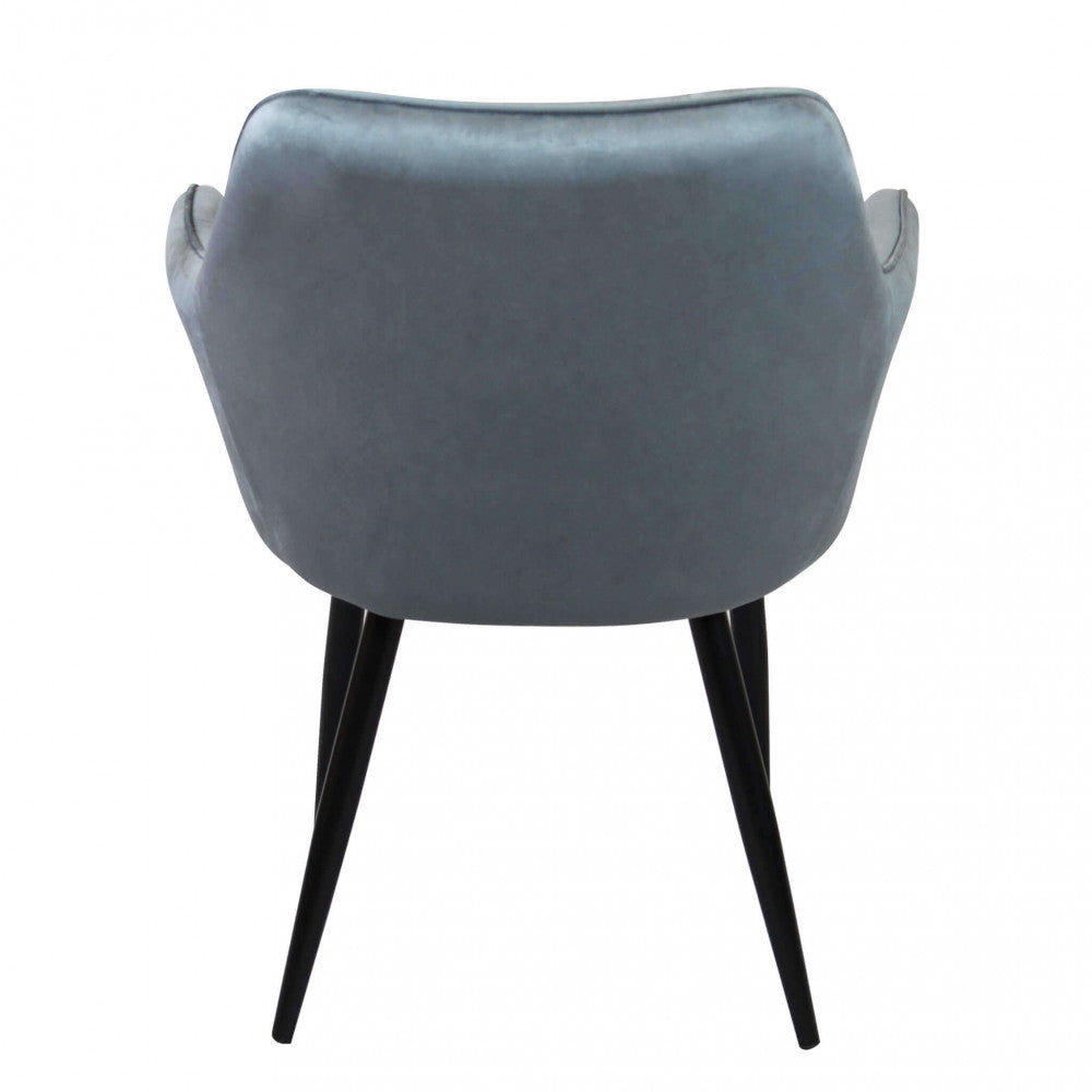 Vista posteriore della poltrona in velluto grigio, mostrando la curvatura ergonomica e le gambe in metallo nero.