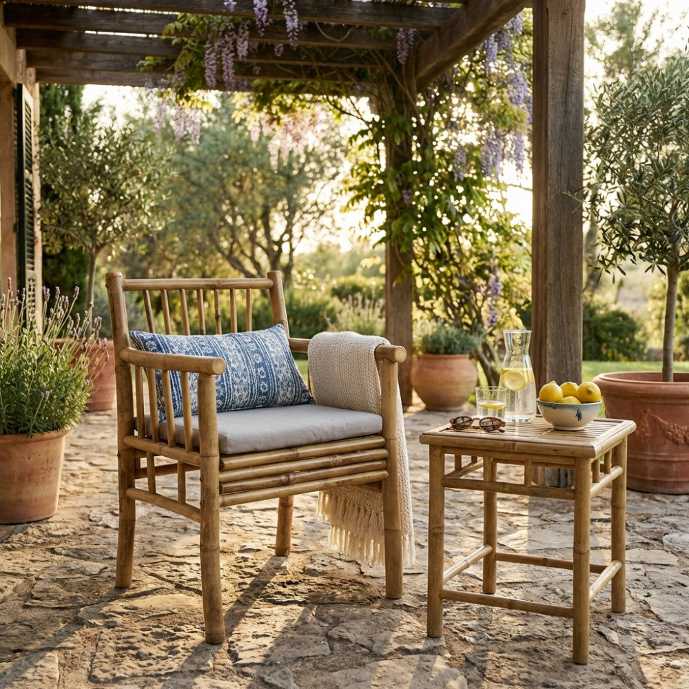 Poltrona CARLIS in bambù impreziosita da un cuscino decorativo blu, posizionata sotto un'elegante pergola all'aperto.