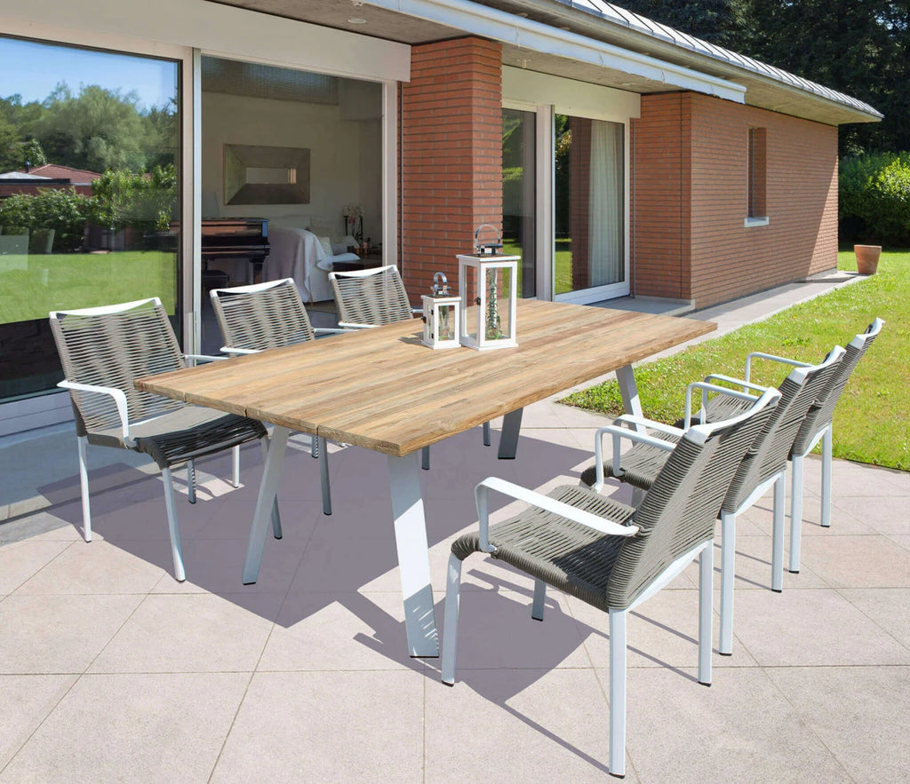 Poltrona Catalina bianca da giardino con design avvolgente e seduta in textilene, ambientata in giardino con tavolo allungabile