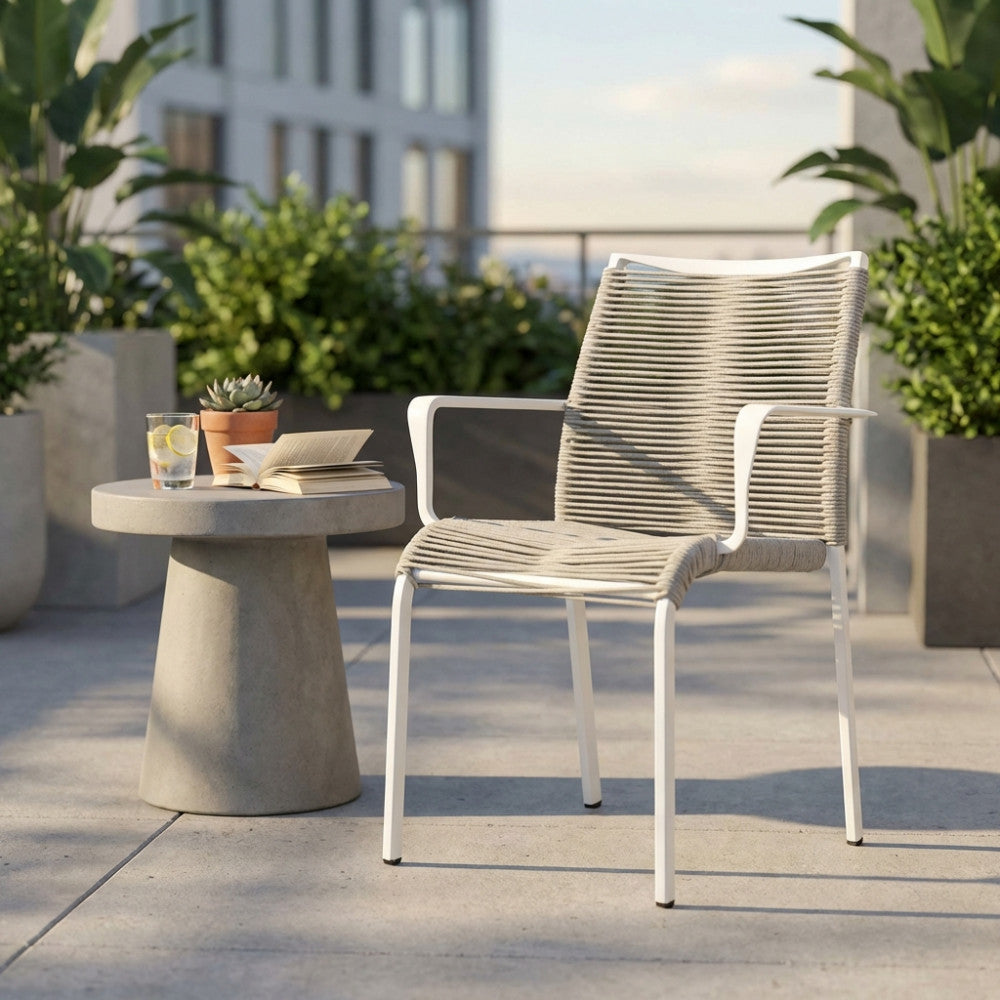 Poltrona Catalina in alluminio bianco e corda grigia, ambientata su una terrazza di lusso con tavolino in cemento e vista metropolitana.
