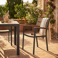 Poltrona CAYMAN in alluminio e polywood taupe ambientata in un patio rustico con tavolo coordinato.