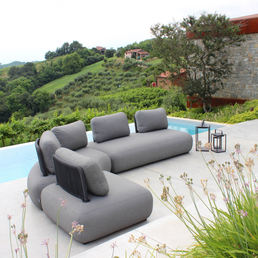 Ampia area lounge esterna a bordo piscina, che mostra una composizione di divani modulari creata con più poltrone Malawi grigie.