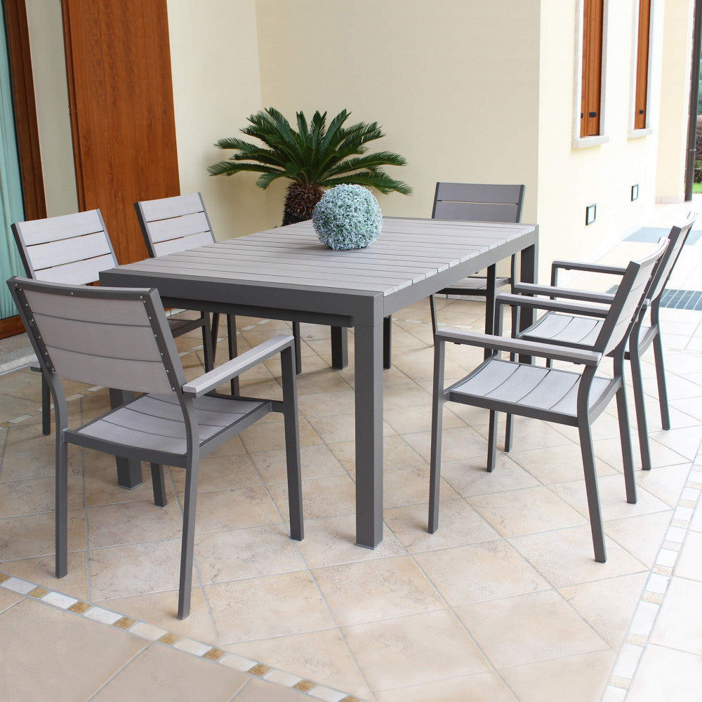 Set da pranzo all'aperto su un patio pavimentato, composto da un tavolo e sei poltrone Cervia impilabili.