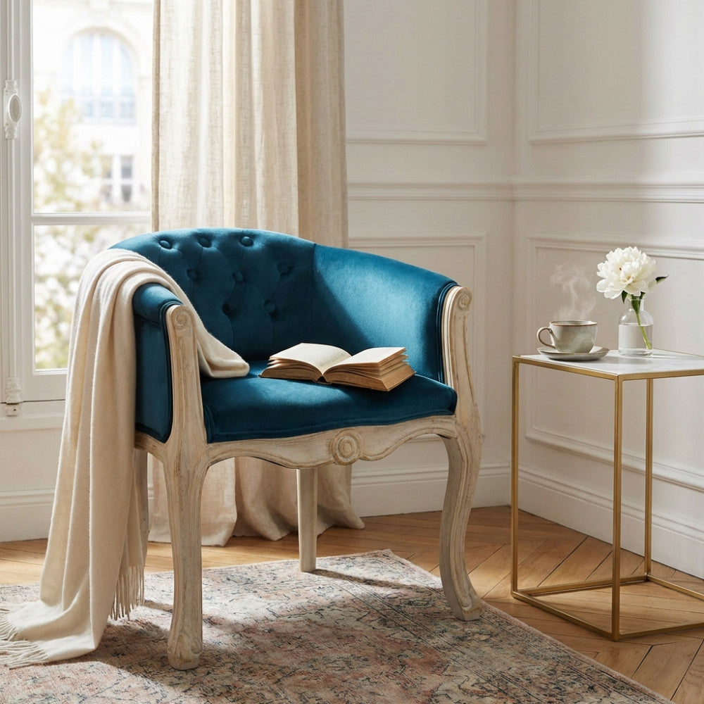 Dettaglio della poltrona Coreen in velluto blu accanto a un tavolino in marmo con tazza di tè.