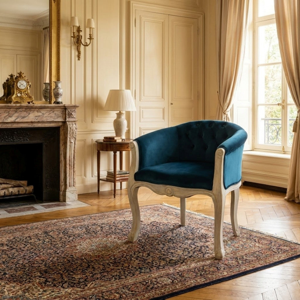 Poltrona Coreen in velluto blu posizionata in un elegante salone classico con camino in marmo.