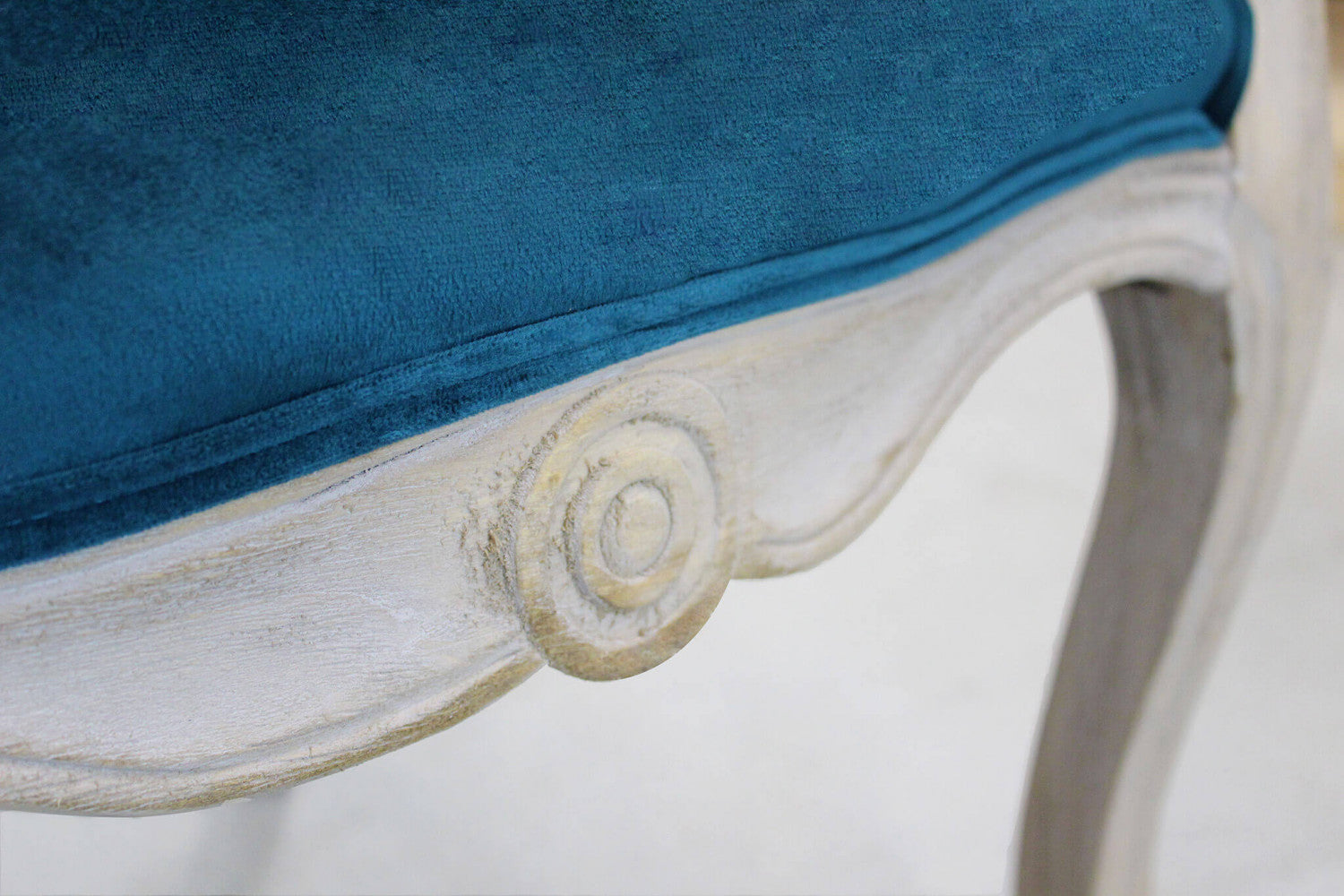 Dettaglio ravvicinato dell'intaglio sul telaio in legno della poltrona Coreen.