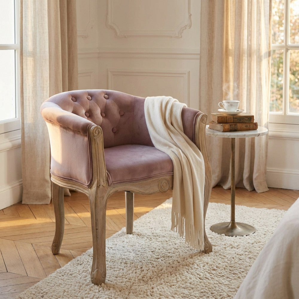 Poltrona Coreen in velluto rosa con coperta bianca, ambientata in un salotto luminoso accanto a un tavolino.