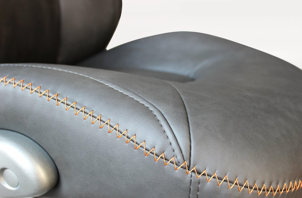 Primo piano sulle cuciture sartoriali a zig-zag della seduta in poliuretano grigio.