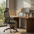 Poltrona da ufficio Tess nera in metallo e plastica, ambientata in uno studio moderno con scrivania in legno, laptop e luce naturale.