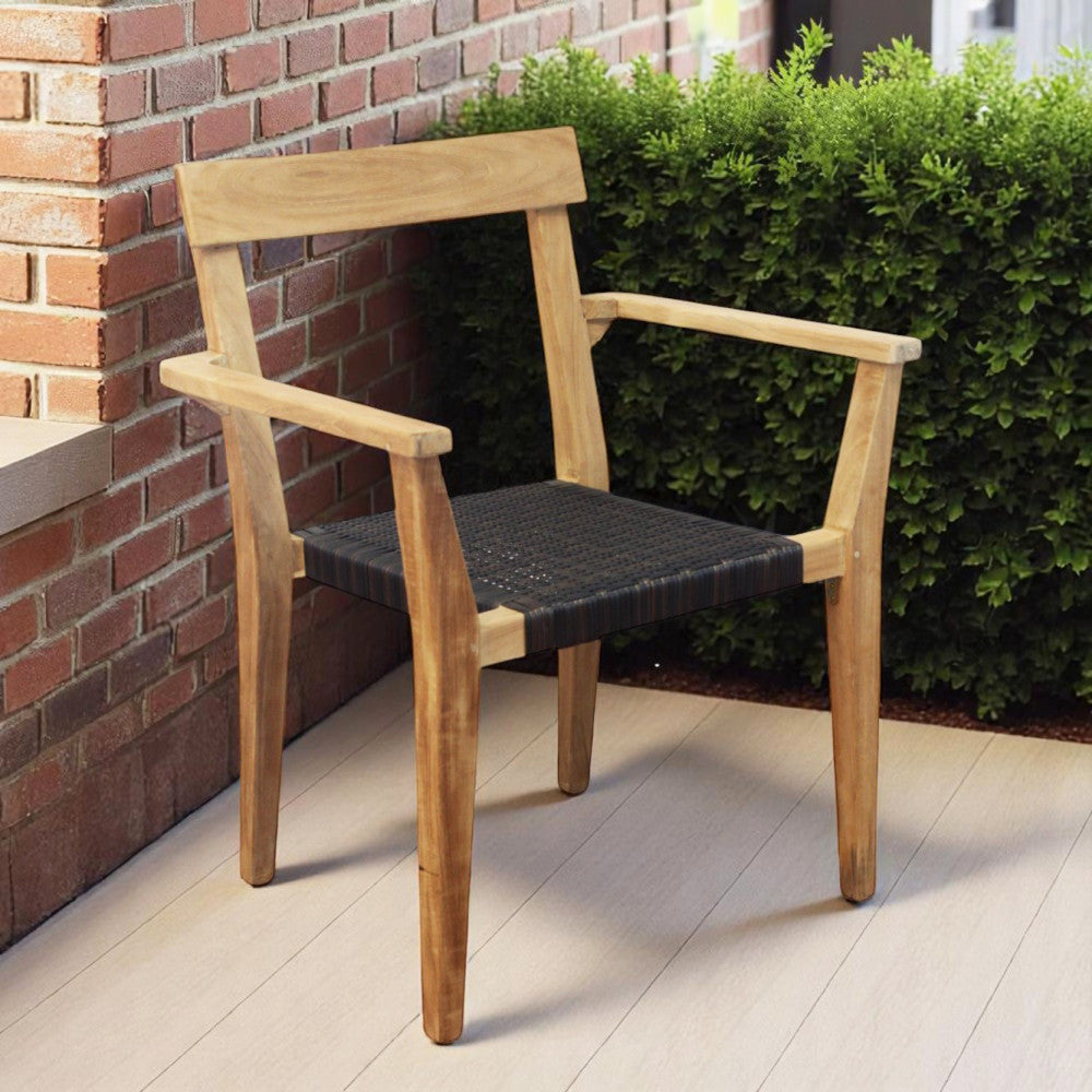 Poltrona Delhi posizionata su una terrazza in legno vicino a una parete in mattoni.