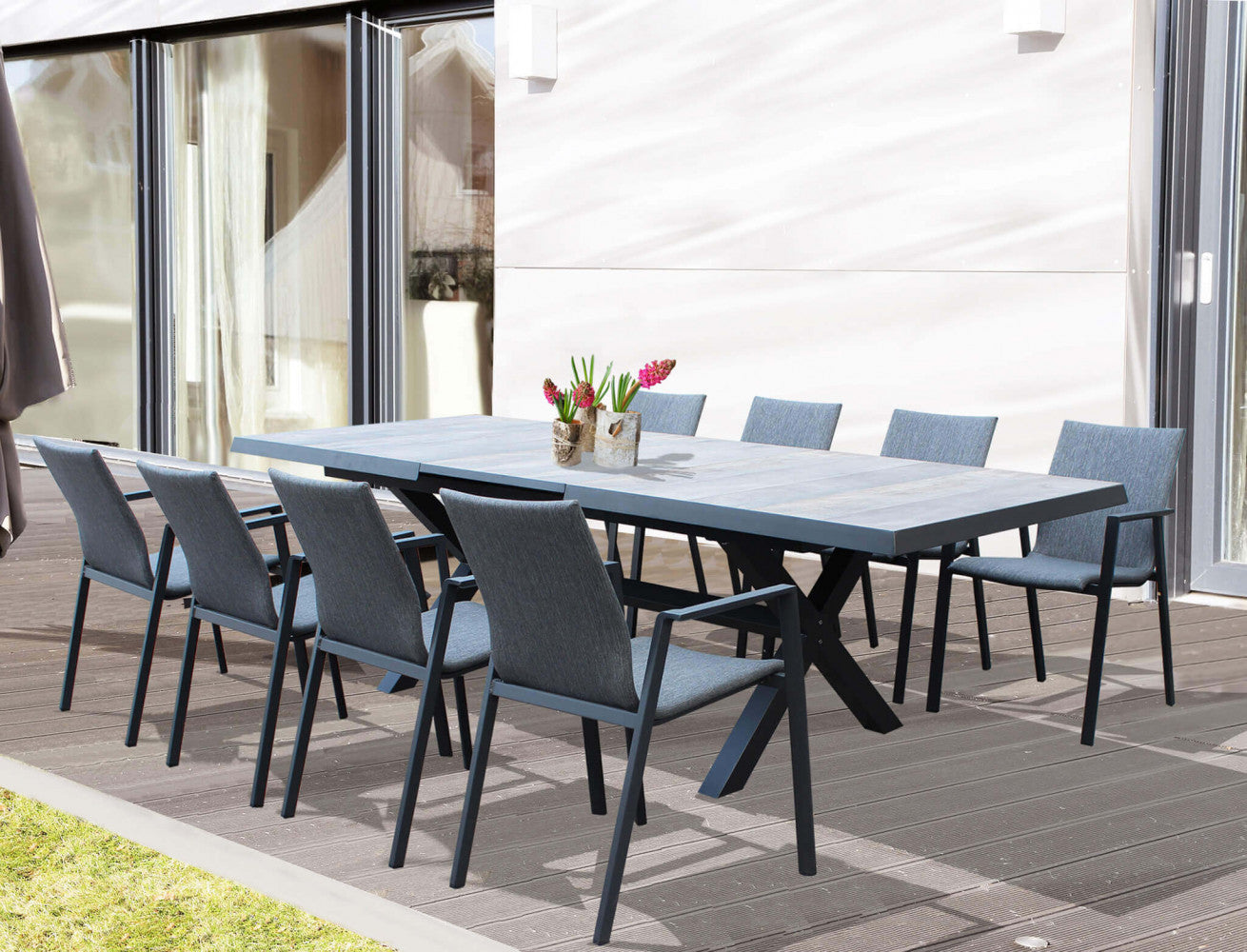 Set da pranzo outdoor con otto poltrone Djerba attorno a un grande tavolo rettangolare su un ponte in legno.