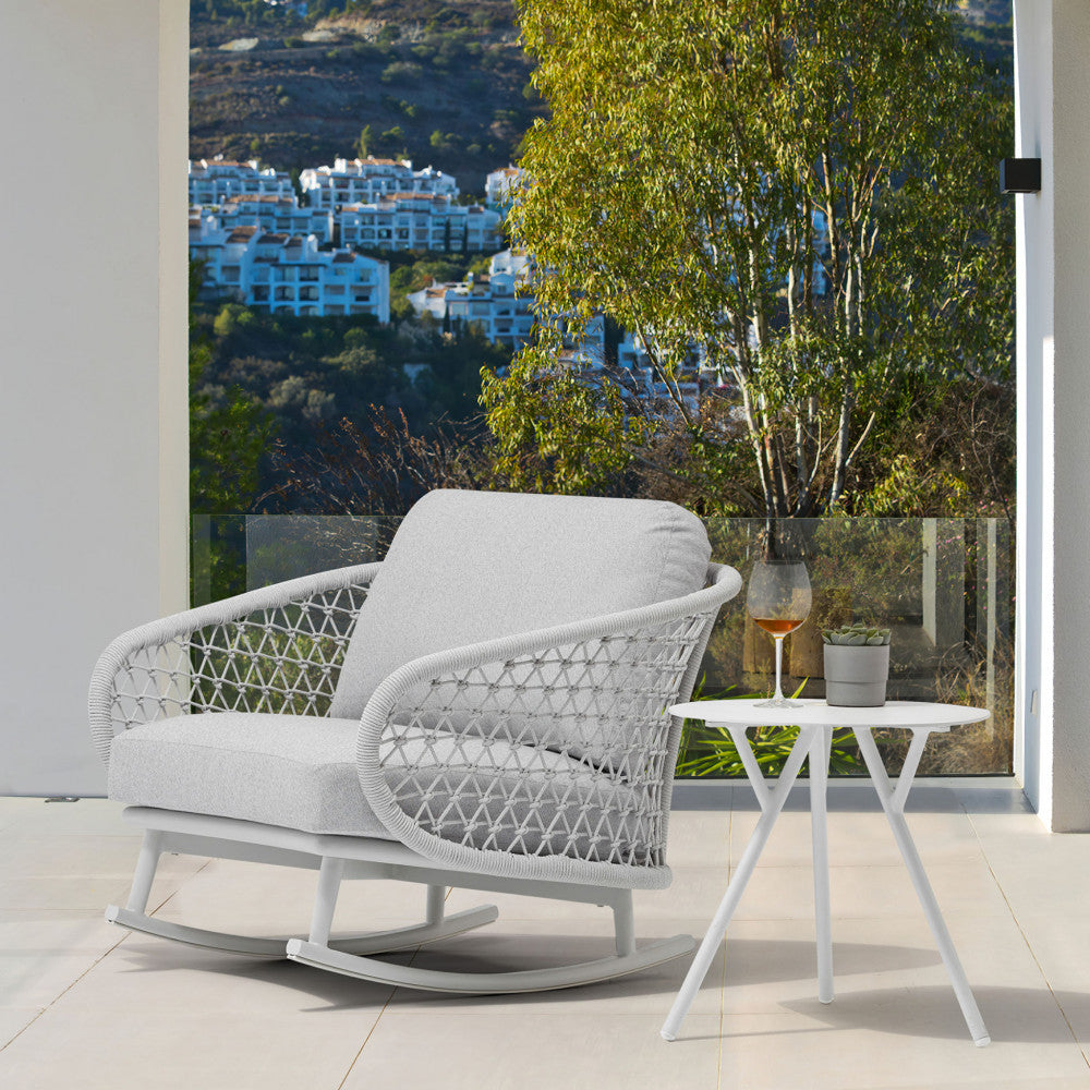 Poltrona relax in corda abbinata a un tavolino bianco su una terrazza panoramica.
