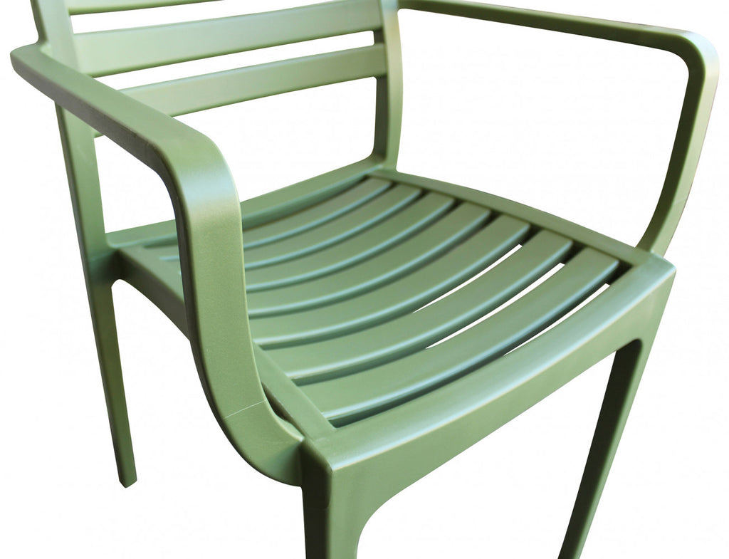 Poltrona Eveline verde scuro in un ambiente esterno elegante e naturale.