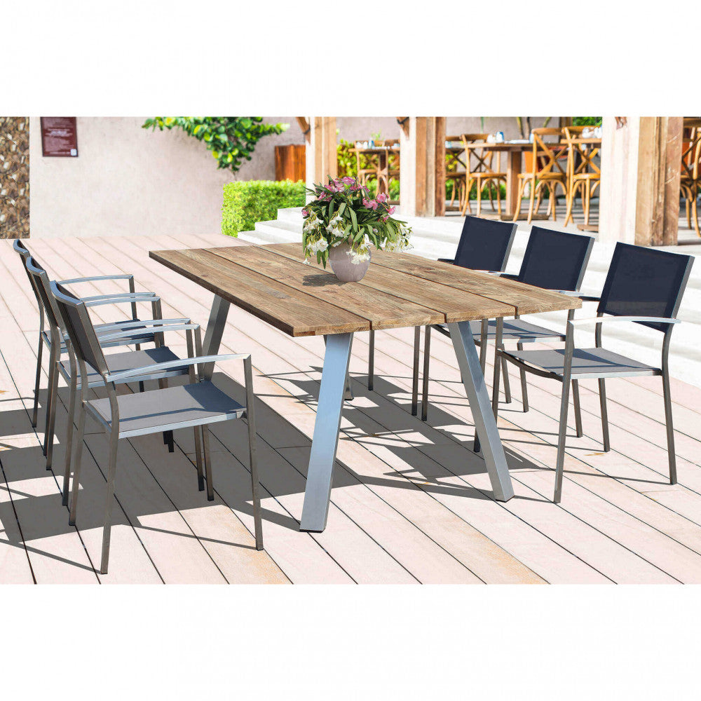 Set da pranzo outdoor composto da sei poltrone Florida in textilene grigio attorno a un grande tavolo in legno massello su un patio soleggiato.