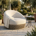 Poltrona girevole Lafayette beige in corda e alluminio ambientata in un patio esterno illuminato dal sole.