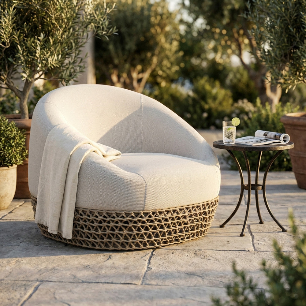 Poltrona girevole Lafayette beige in corda e alluminio ambientata in un patio esterno illuminato dal sole.