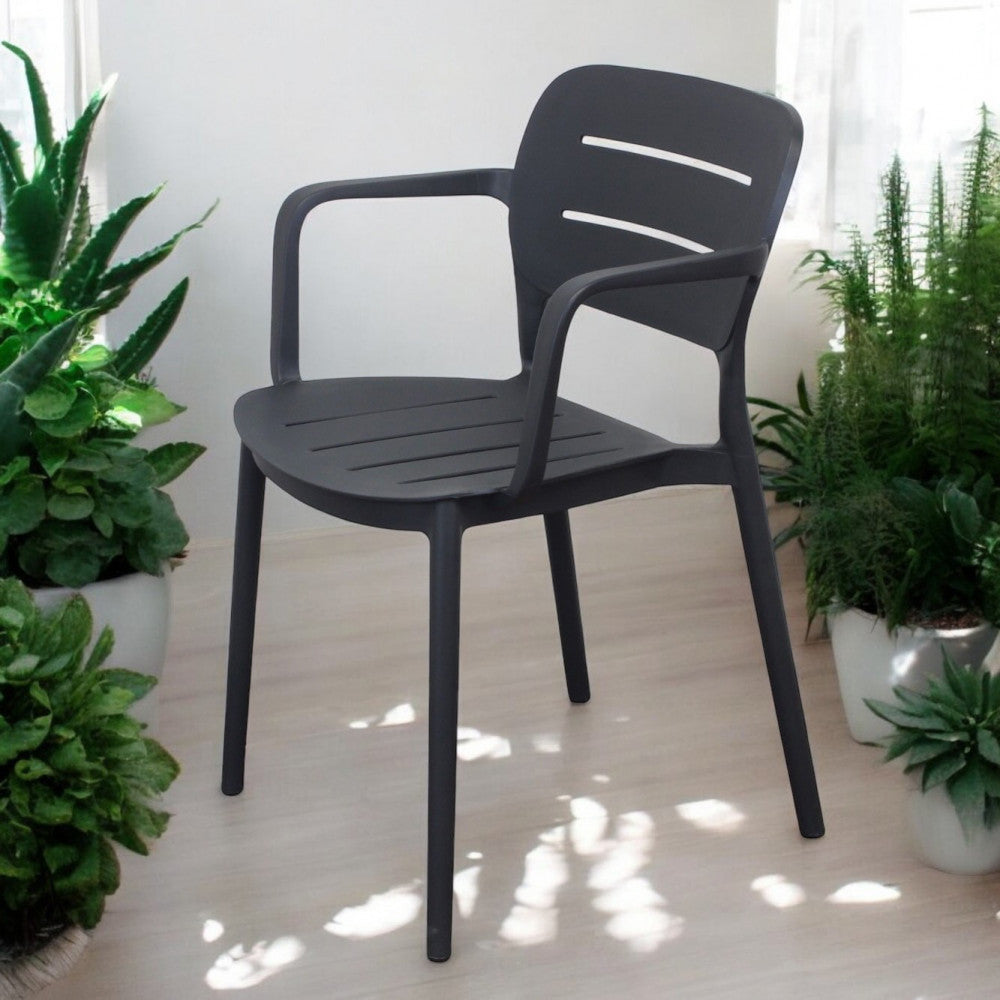 Poltrona Giselle antracite inserita in un luminoso giardino d'inverno circondata da piante verdi in vaso.