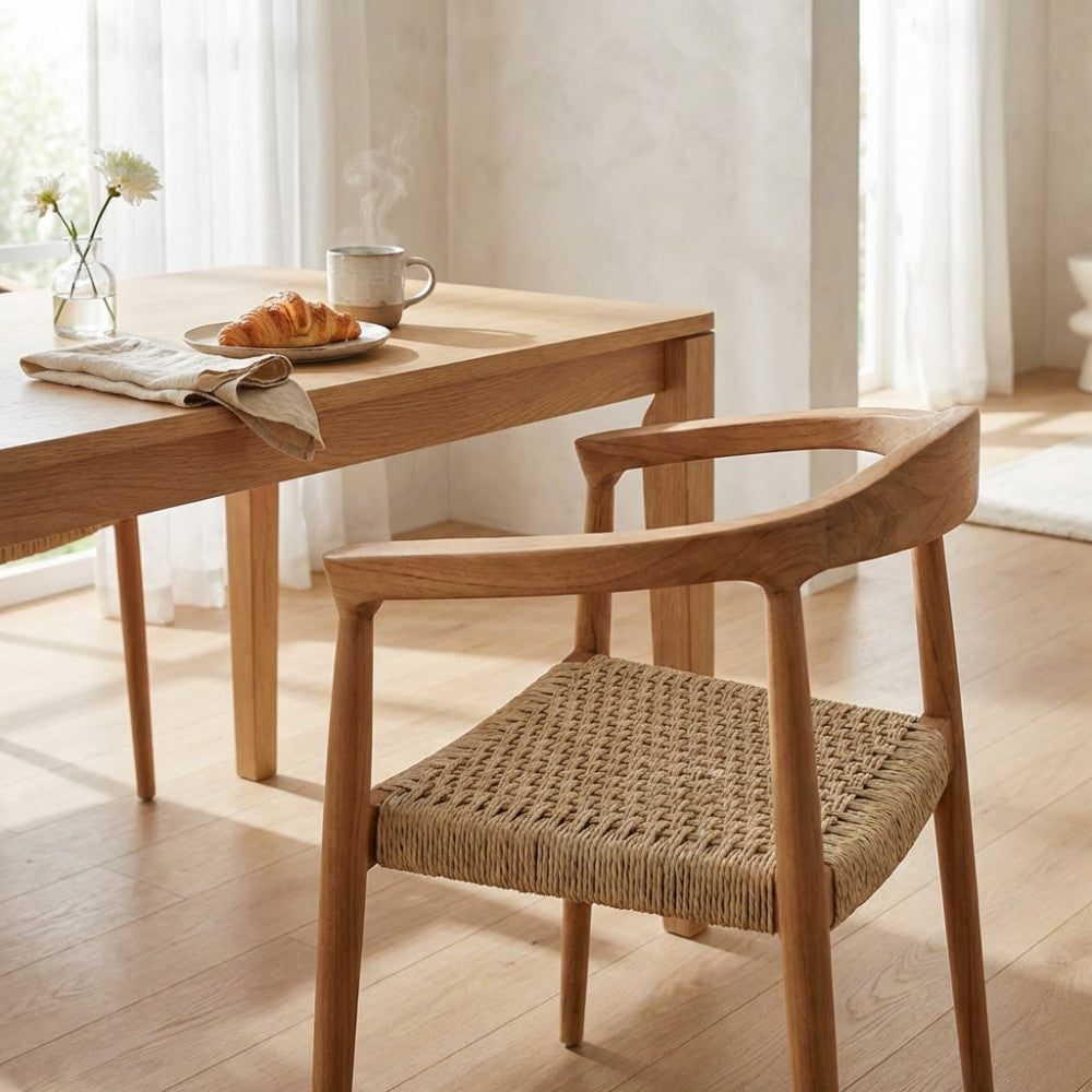 Poltrona Harvard in teak posizionata accanto a un tavolo da pranzo in legno in un ambiente interno luminoso e soleggiato.