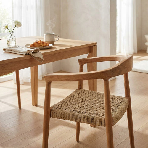 Poltrona Harvard in teak posizionata accanto a un tavolo da pranzo in legno in un ambiente interno luminoso e soleggiato.