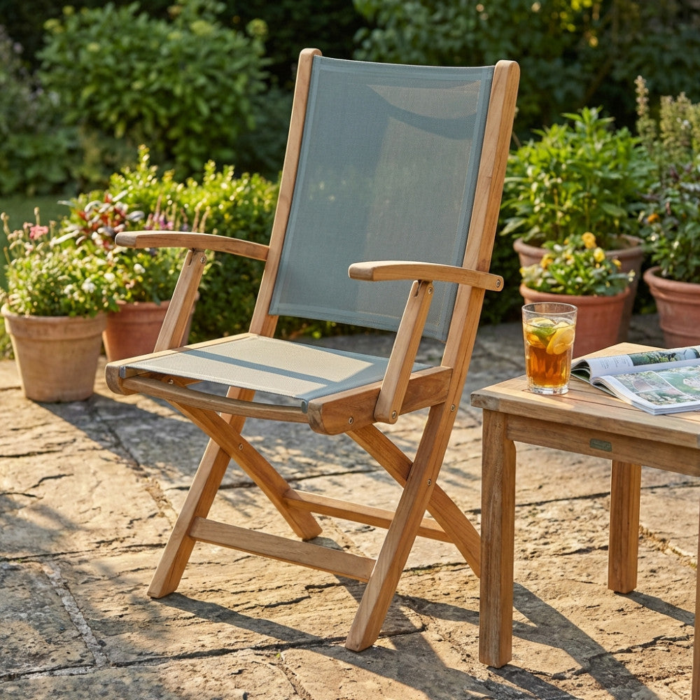 Vista frontale angolata della poltrona Lahore in teak, posizionata su una pavimentazione in pietra naturale all'aperto.
